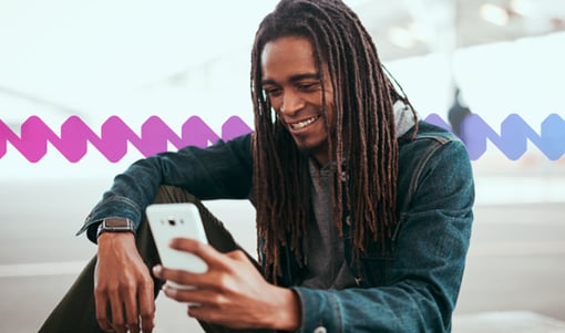 Man sitting and smiling while using his mobile device